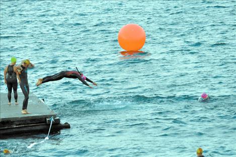 A woman triathlon participant jumps into Flathead Lake. 