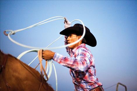 A Flathead River Tour Rodeo  cowboy twirls his rope as he warms up for the compeition. 