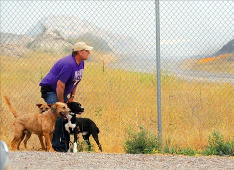 Bob Kintz, Mission Valley Animal Shelter employee, waits for volunteers to take three of 14 dogs from the shelter to a safe home for the night as a grassfire burns near the building. 