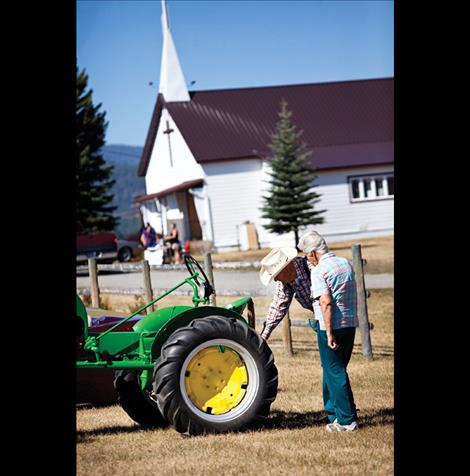 Folks enjoy perusing oldtime tractor.