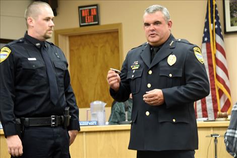 Polson Police Chief Wade Nash, right, presents new Polson officer Mathieu Gfroerer his pin.