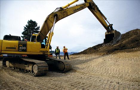 Construction workers direct a Komatsu 400 excavator on the Polson Walmart Supercenter construction project.
