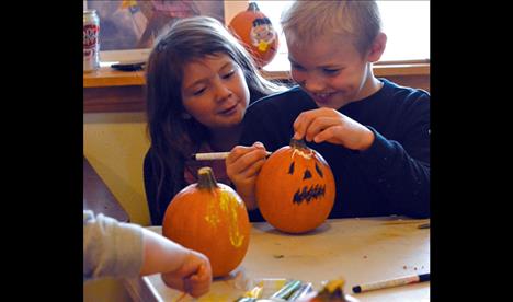 With an interested friend viewing over his shoulder, Caydan Clark, 8, decorates his pumpkin 