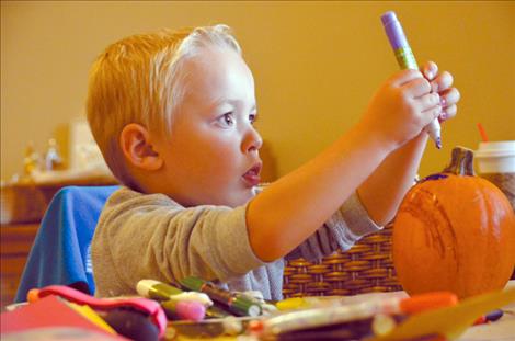 Caleb Clark, 3, concentrates intently as he works on decorating a pumpkin.