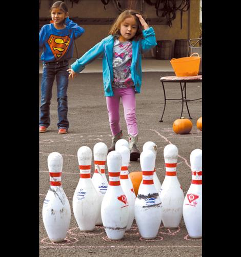 Children enjoy tossing pumpkins down a make believe alley as they play pumpkin bowling.