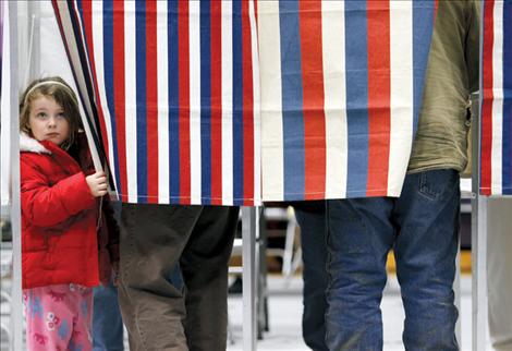 Four-year-old Olivia Fleming peeks out of a voting booth while dad Thomas fills out his ballot Nov. 6 in Polson. 