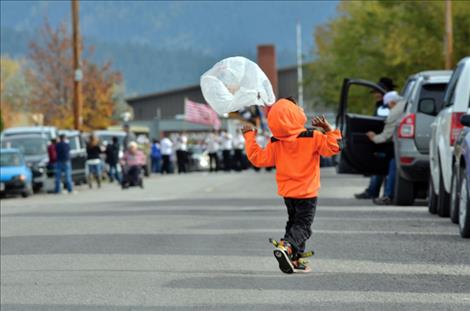 A child plays with an empty candy bag while waiting for the parade to arrive.