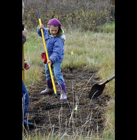 Natalie Helser, 10, works the soil to get it ready for planting.