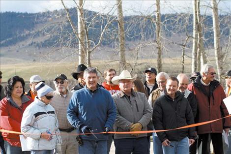 Construction workers, Tribal Council members, engineers from the CSKT, DJ&A and the county, local residents and county commissioners smile moments before the ribbon- cutting.