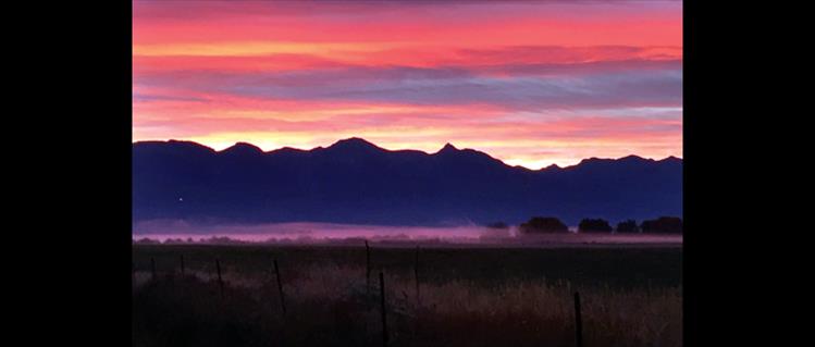 Sunrise illuminates a strip of fog in the valley