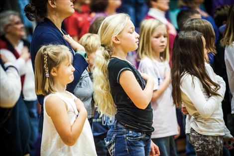Students stand for the Pledge of Allegiance during their Veterans Day ceremony.