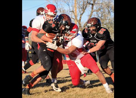 Arlee Warriors Bradley Brazill, left, and Patrick Bigsam tackle a Chinook Sugar Beeter player during Saturday’s state championship game.