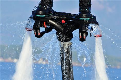 A thick hose attached to a board, provides water that sprays out from under a flyboarder’s feet.