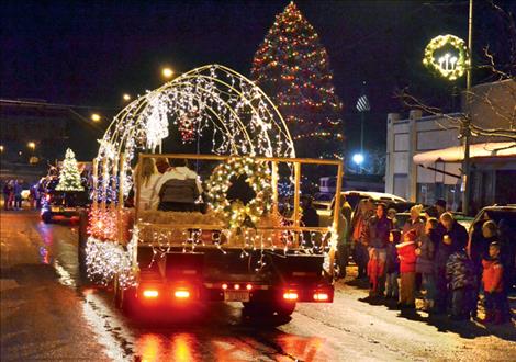 People bundle up and watch as brightly-lit floats head down Main Street in Ronan.