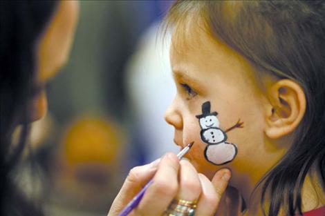 RaLynn Brown paints a snowman on Kaycee Best’s cheek during the annual St. Ignatius Chamber of Commerce Christmas Carnival.