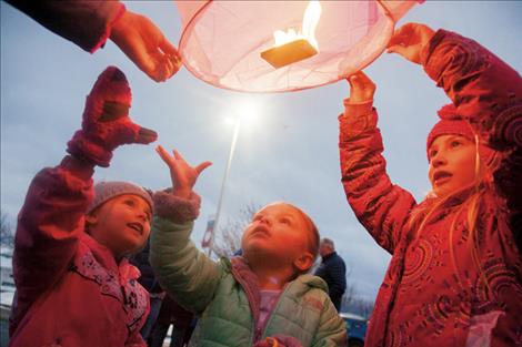 Children watch a lantern get ready to take off into the sky.