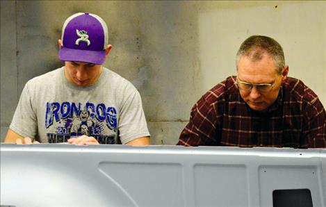 Shop teacher Stan Atchley gives student Toby Odom a few words of advice as they sand the car.