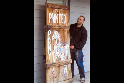 Geoff Rohrlach carefully adjusts the gallery’s new sign made from an old barn door.