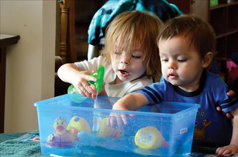 Jacob Pete, 2, and Joshua Pete, 1, race their rubber ducks in a bucket of water. 