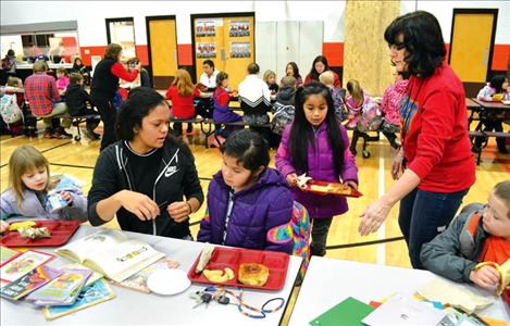 Peggy Rowe helps children find a table with a volunteer reader. 