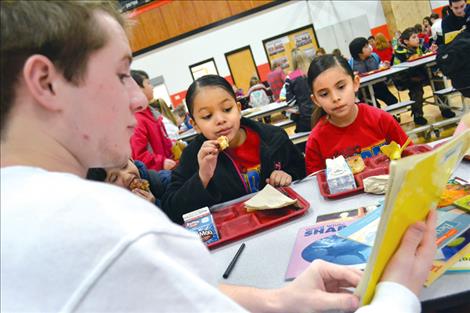 anner Olson, one of several Ronan High School National Honor Society students, shares a book with sisters Fancee and Cynthia Oldperson Friday morning at K. William Harvey Elementary School in Ronan.