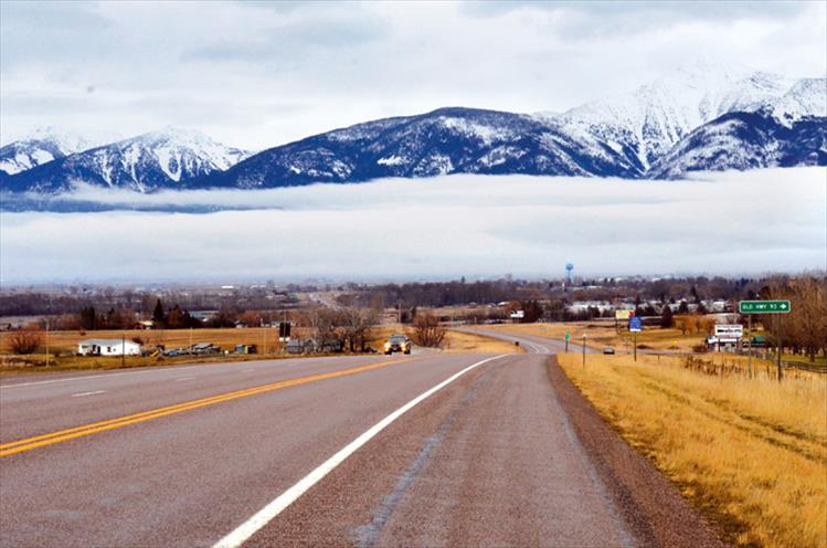 A layer of fog hugging the base of the Mission Mountain Range appears to draw a line between the valley floor and the mountain peaks.