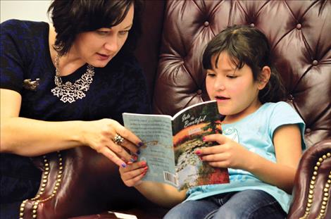 Teacher Francy Moll helps student Haivyn Runsabove during the poetry reading.