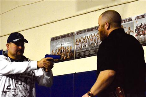 St. Ignatius Police Chief Matthew Connelly helps Officer Levi Read demonstrates how to grab a gun.