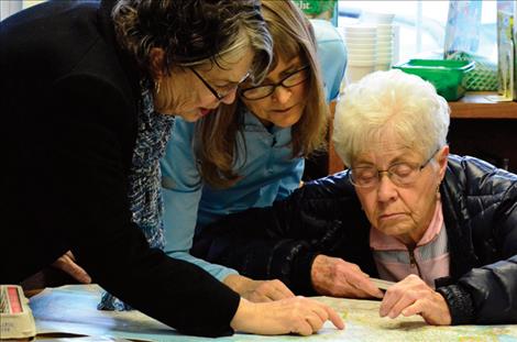 Renee Loehr, Donna Cheff and Lucille Ashby look for a location on a map related to the book. 