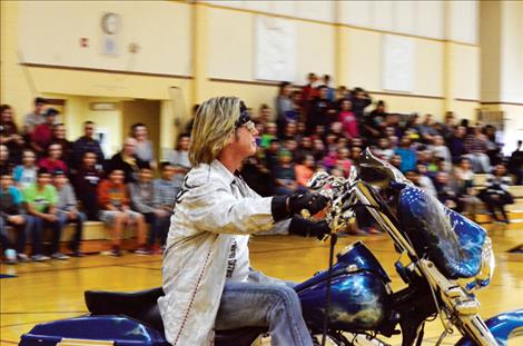 Flash rides into the junior high gym on a motorcycle to talk about bully prevention.