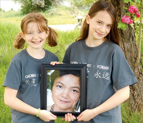 Helen and Hailey Smith show off a photo of their new sister from China.