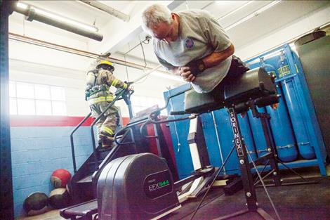 Chris McGuinness works his core while Julie Sisler climbs the stairs to train for the fundraiser.