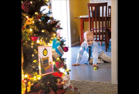 Cole Whitworth, 6, plays with a tiny car in front of the Christmas tree. Cole is undergoing treatment for medullablastoma, a brain tumor affecting mainly children, and First Interstate Bank staff thought the tree would cheer him up.