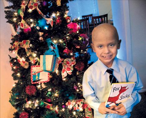 Cole Whitworth hold “Fox in Sox,” one of his favorite Dr. Seuss books, in front of a Dr. Seuss-themed Christmas tree, a gift to Cole and his family from First Interstate Bank.