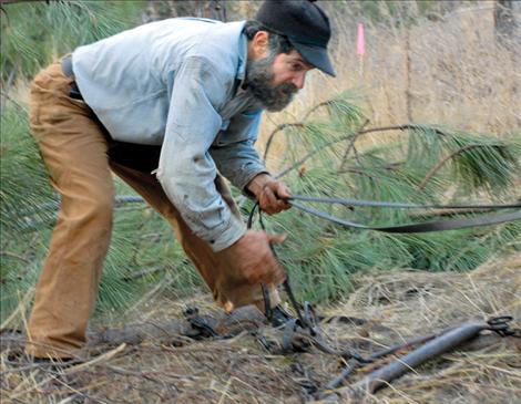 David Sturman hooks a chain to a tree while keeping hold of the reins. 