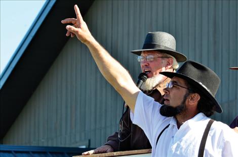 Auctioneers take bids on many items including a pig and a rocking chair.