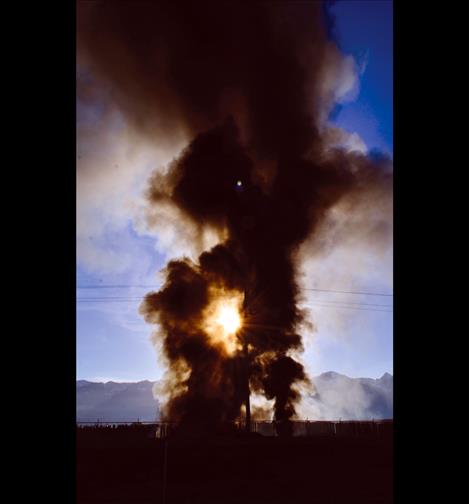 The sun peeks through black smoke rising early Friday morning from the Tire Depot fire.