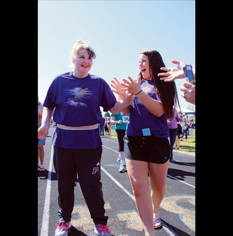 Jenna Evertz, right, cheers on Fayth Loveless as she crosses the finish line