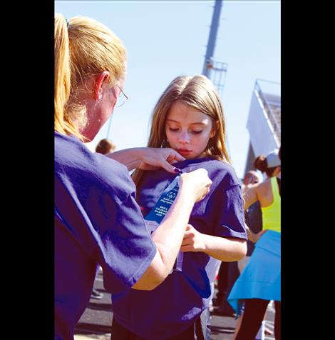 Melesa Butler pins on Victoria Niblack’s first-place ribbon for the 50-meter run.