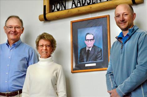 Gordon, Ann and Eric Henricksen stand with a photo of dealership founder Don Aadsen. 