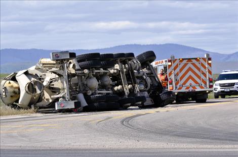 Emergency crews respond to a wreck  where a full cement truck is flipped  on its side