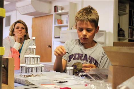 Brock Sturm, center, helps assemble a GearPod survival kit in his family basement. .