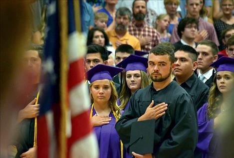 Graduates salute as the Polson Concert Choir sings “The Star Spangled Banner.”