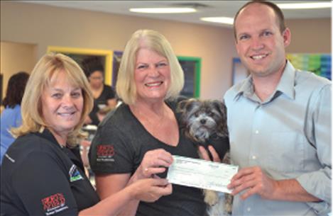 Clearwater Montana Properties Realtor Kathy Crockett, left, and Broker Carol Tibbles (with her pup Boots) present a check to Aric Cooksley, executive director of the Boys and Girls Club of the Flathead Reservation and Lake County.