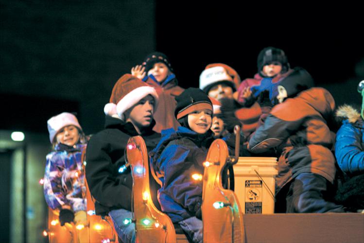 Children and grandchildren of the Bartel, McClure and Shima families smile and wave in the Starlite Motel’s Santa sleigh float. 