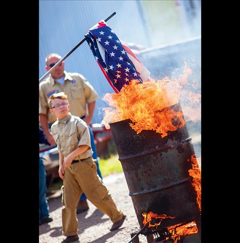 A Boy Scout watches as stacks of worn flags are burned in respect.
