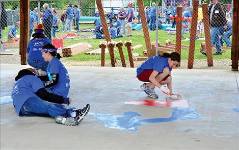 Volunteers paint a map of the United States under the pavillion to help create a play space for Mission Elementary School students.