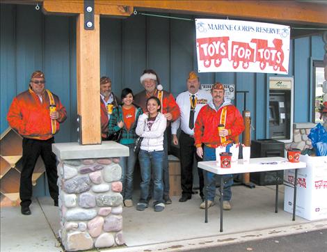 Marines Dennis Corbitt, Tim Orr, Frank Butler, John Miller and Rick Marquart stand outside a Toys for Tots donation center with two volunteers.