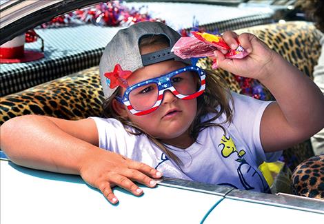Paige Miller tosses candy from a classic car.