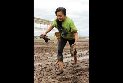 Marygold Houk removes her mud-caked shoes to finish, and below right, scrambles over a fence obstacle.